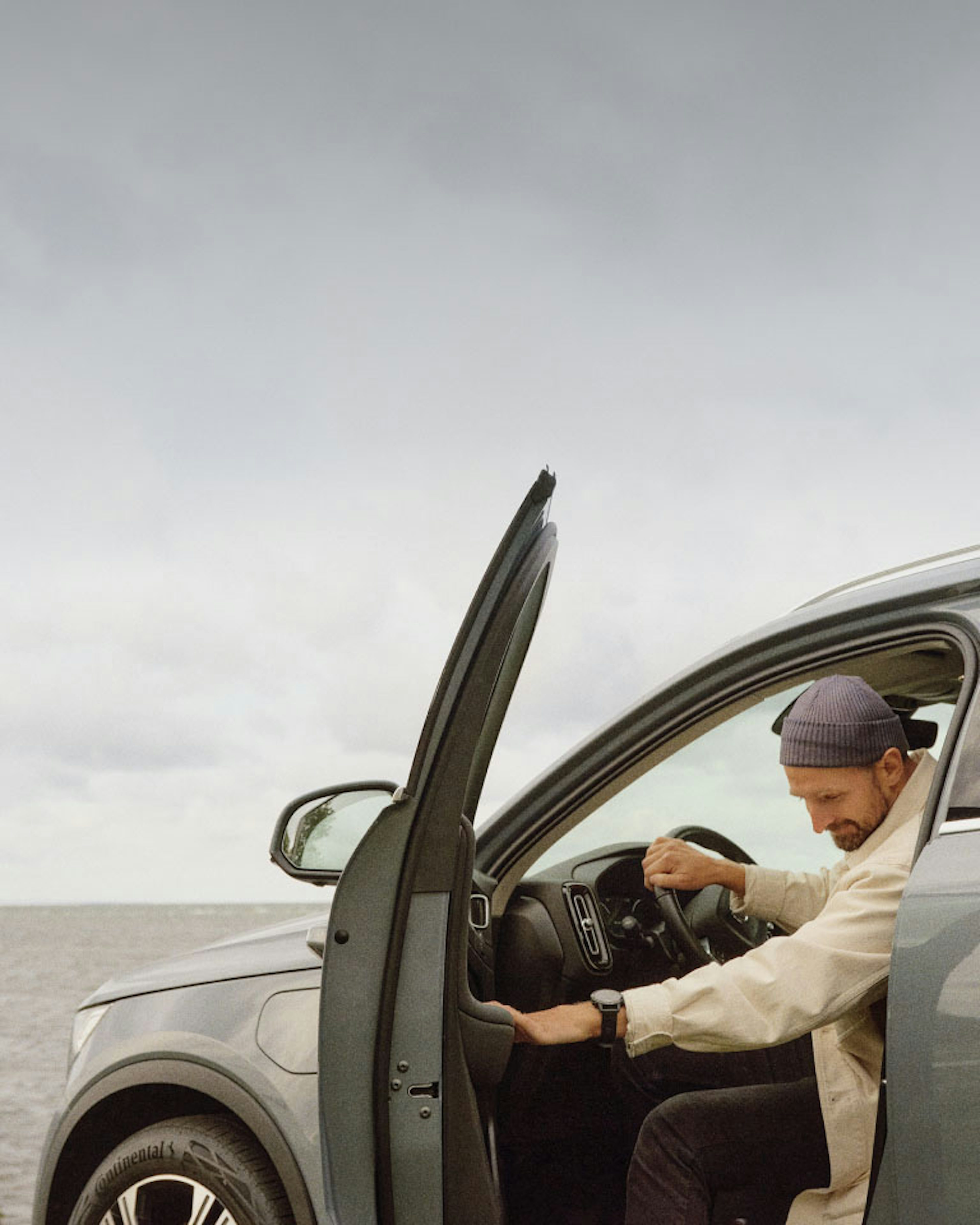 Man with a gray beanie about to exit the driver’s seat of a Volvo