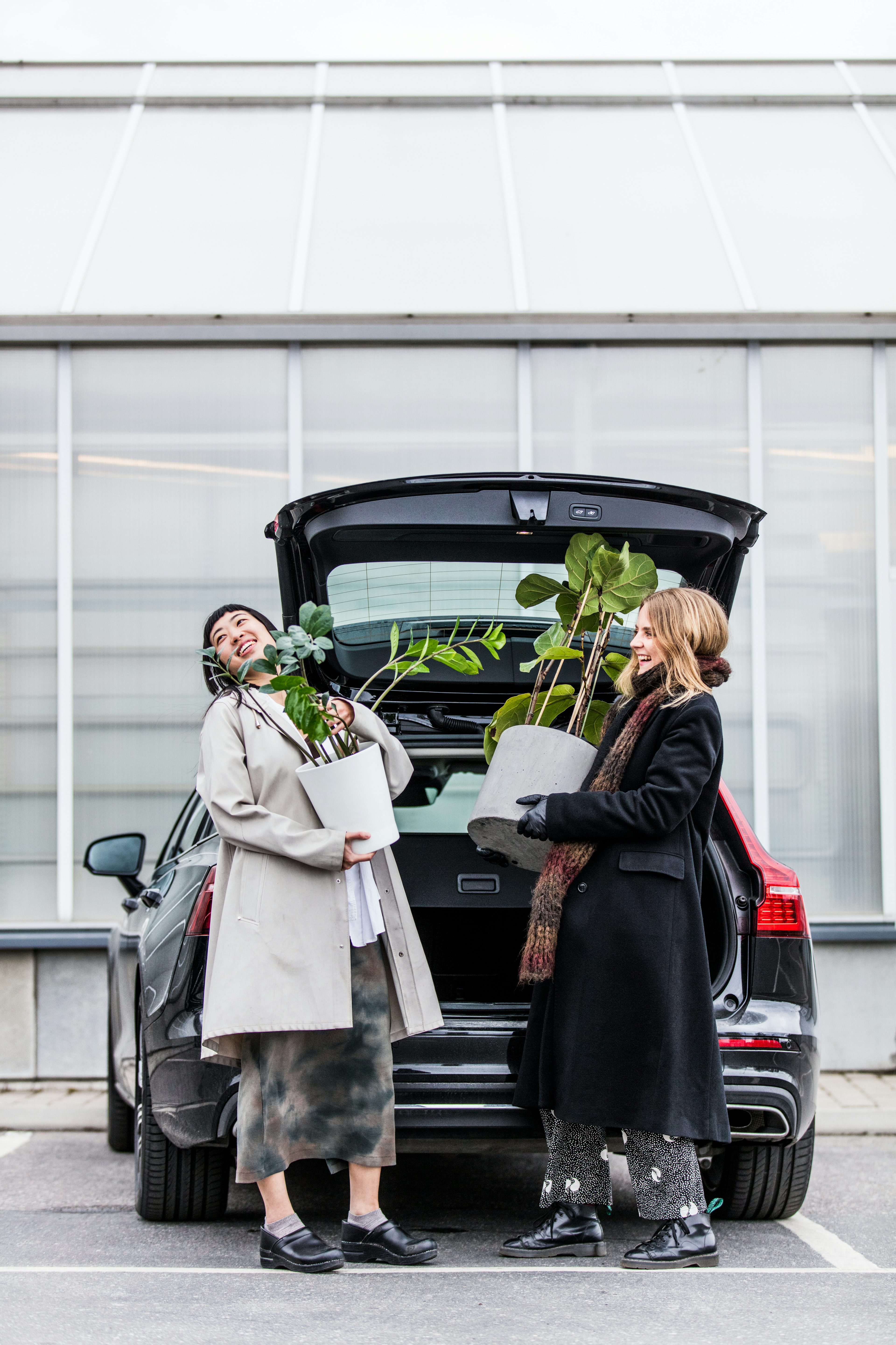 Två kvinnor lastar ur växter ur bakluckan på en Volvo.