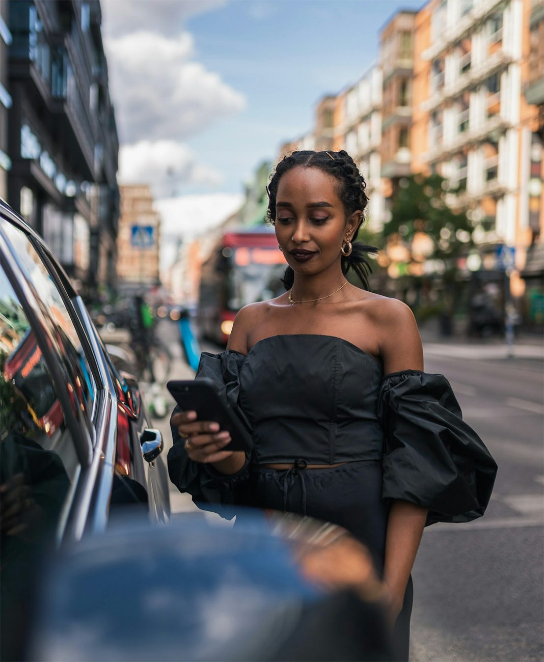 En kvinna står vid en bil på en stadsgata och låser upp sin bil med Volvo On Demand-appen.