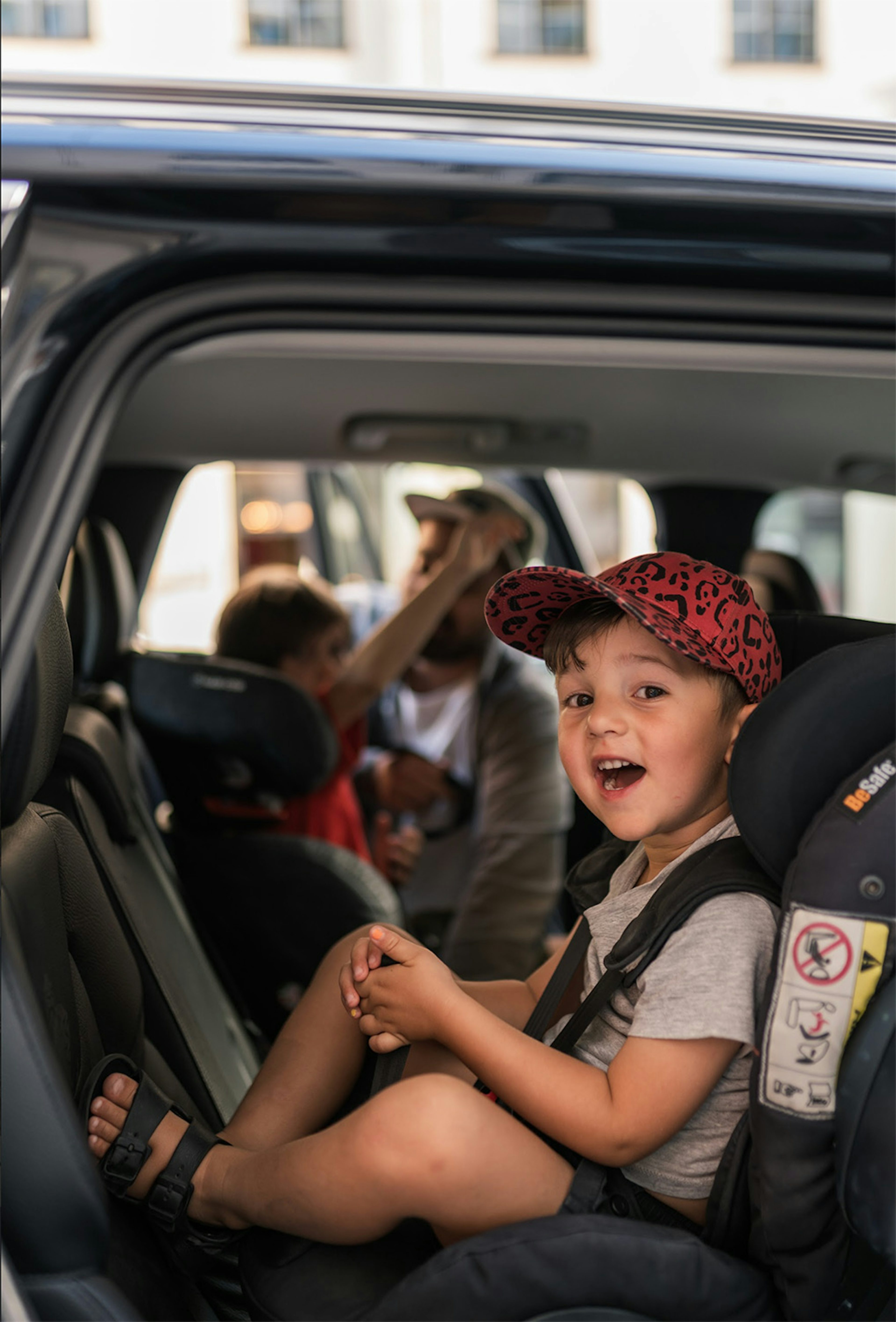 Ett leende barn sitter i en bilbarnstol i baksätet på en Volvo.