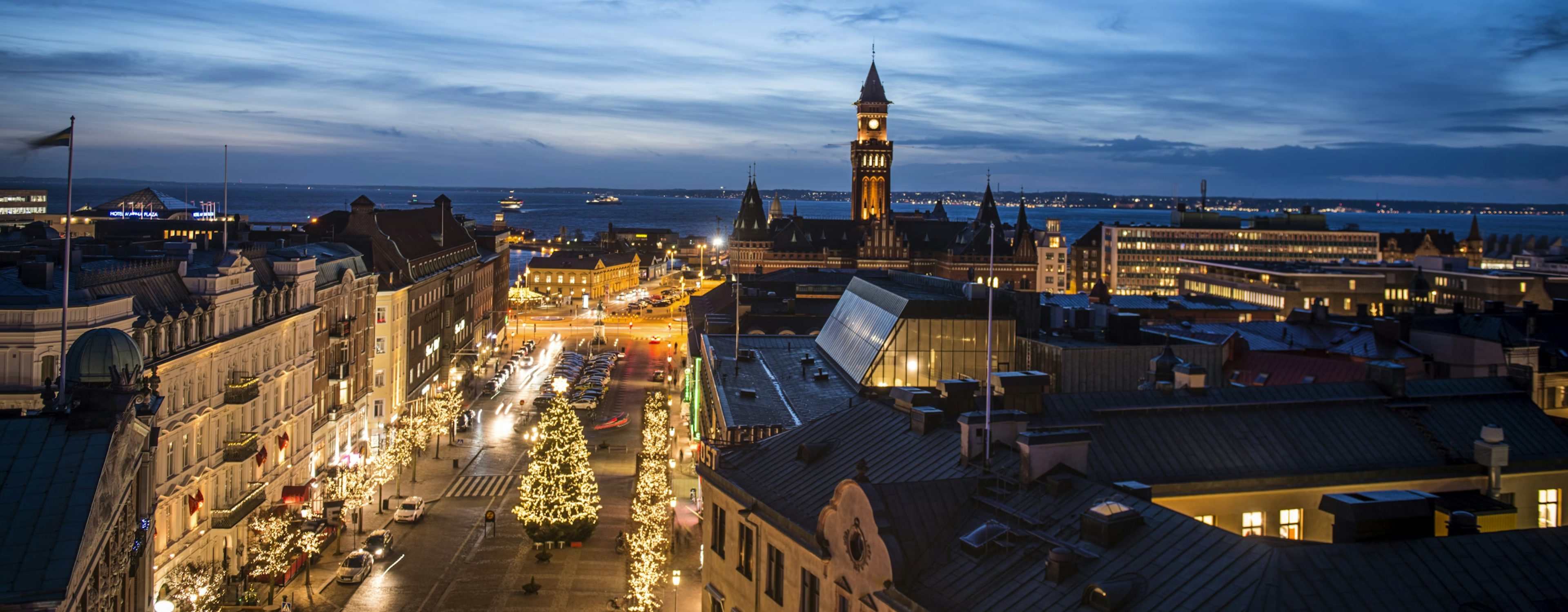 Kvällsvy över Helsingborgs stadskärna med julbelysning längs gatorna och utsikt över Öresund
