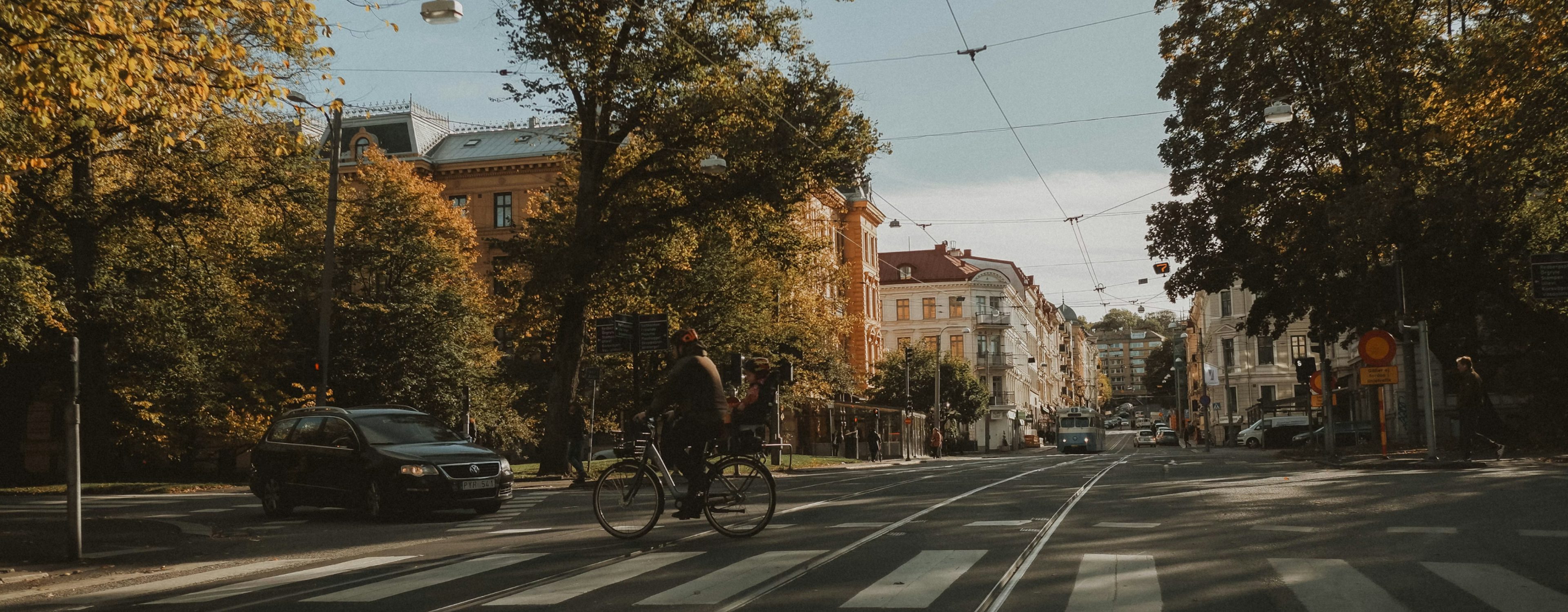 Livlig gata i Göteborg med cyklister och bilar, omgiven av klassiska byggnader och höstträd